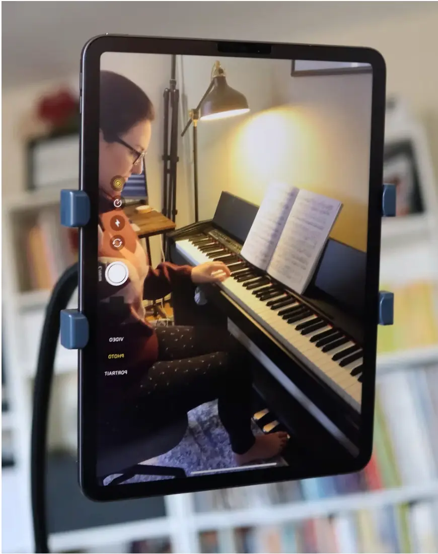 iPad on a floor stand showing a student playing piano from the side — perfect camera angle for online music lessons and RCM exams